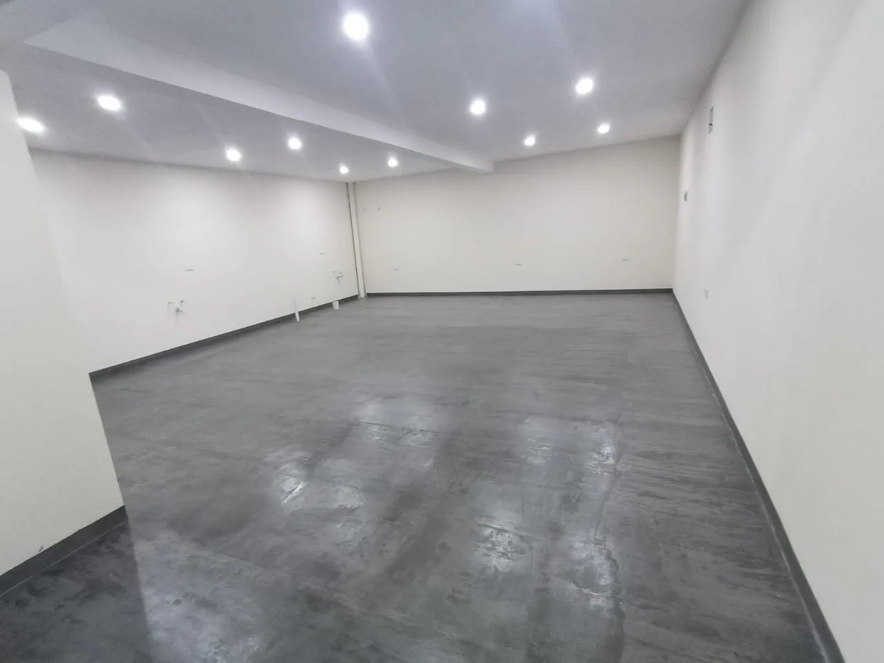 Large empty room with white walls and grey floor