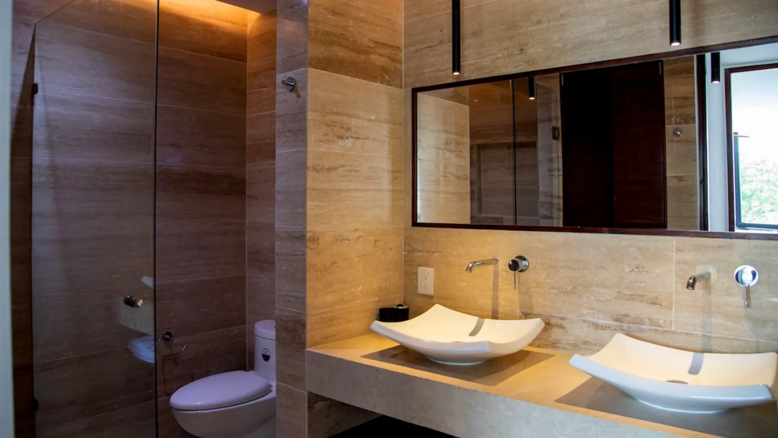 Modern bathroom with dual vessel sinks and stone walls
