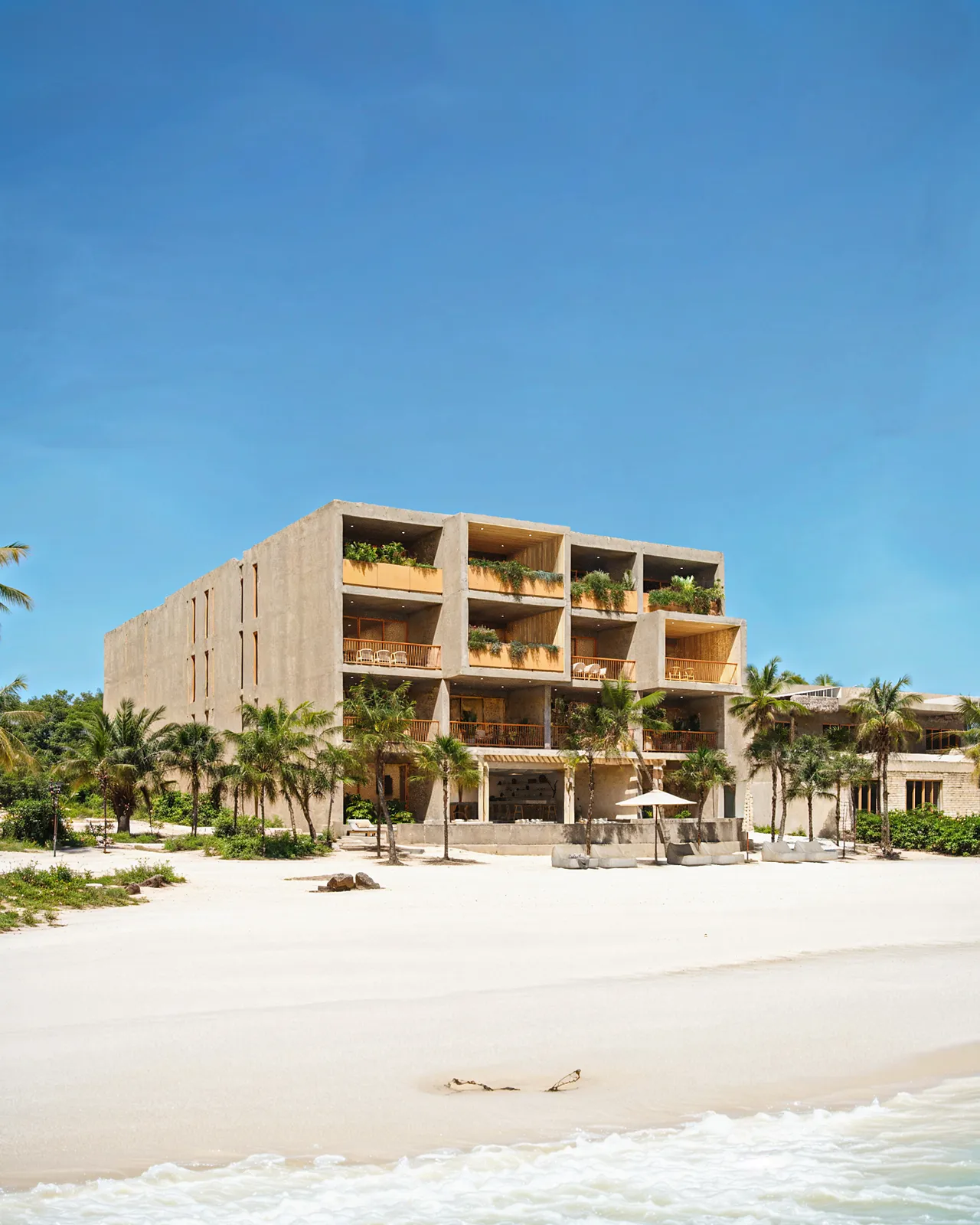 Modern concrete building on a sandy beach with palm trees