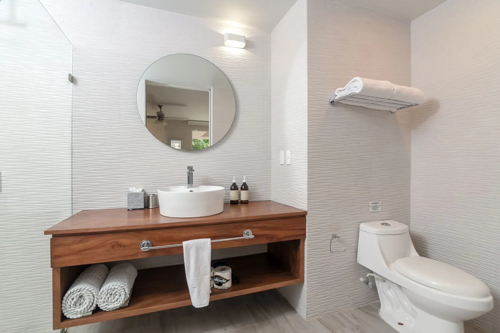 Modern bathroom with wooden vanity and round mirror