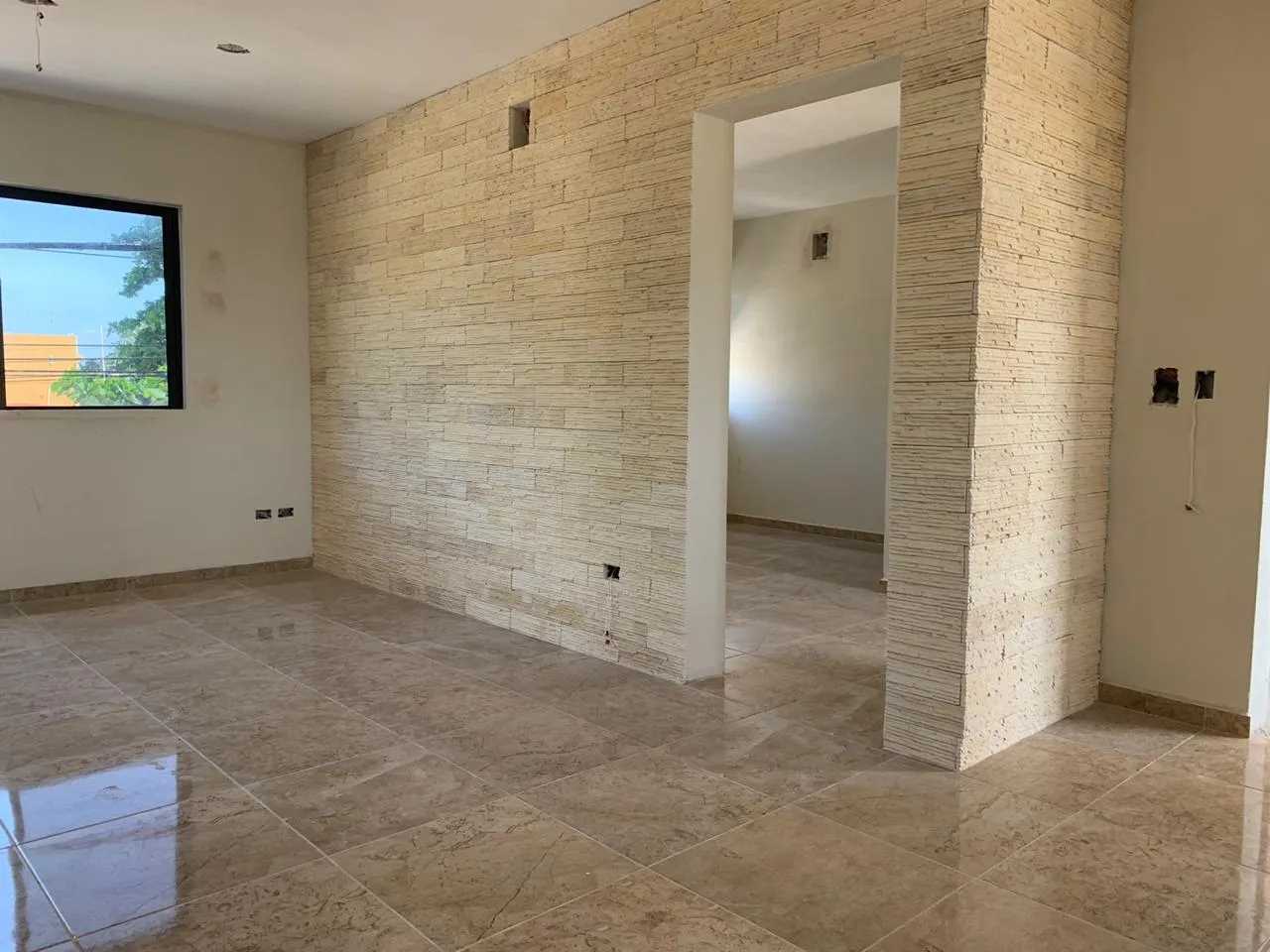 Empty room featuring a stone accent wall and tiled floor