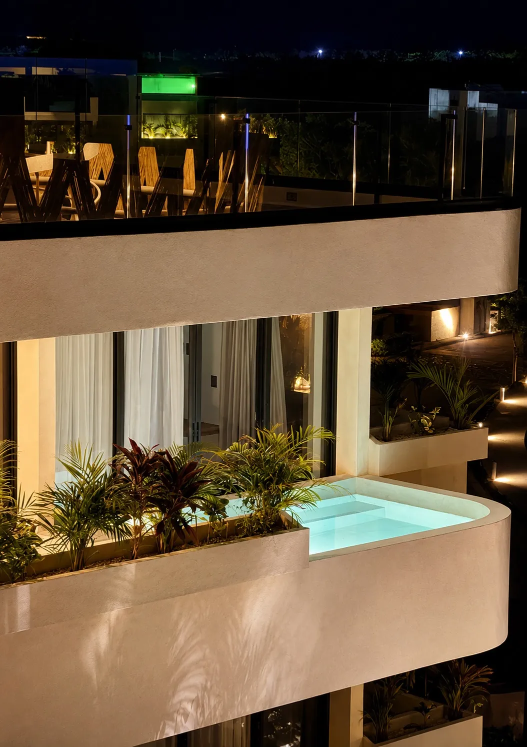 Modern building exterior with illuminated plunge pool and balcony