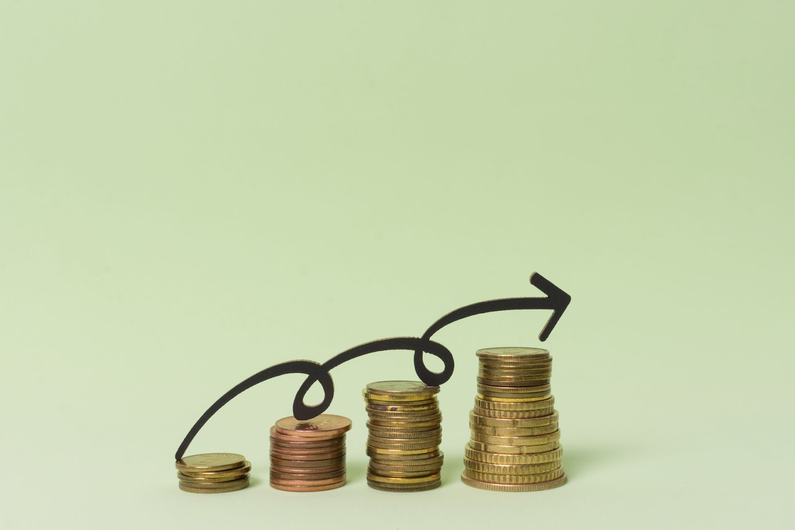 Gráfico de crecimiento financiero con monedas apiladas y flecha ascendente sobre fondo verde