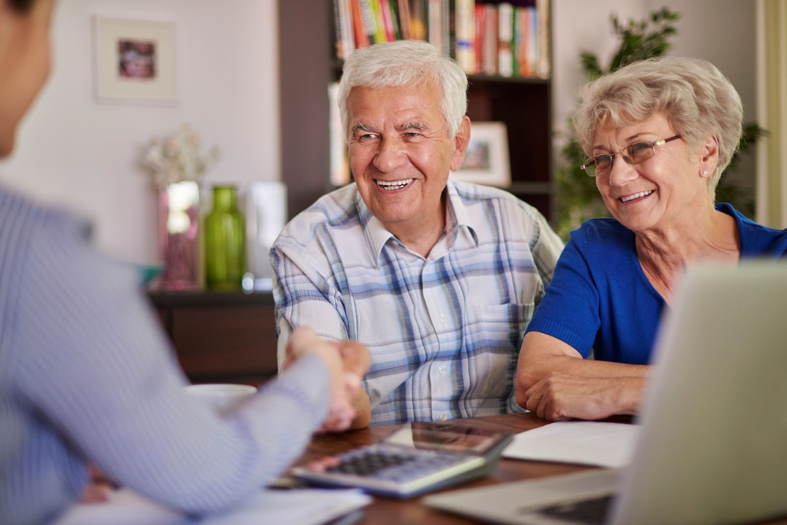 Pareja de adultos mayores sonrientes consultando con asesor financiero sobre planificación de pensiones