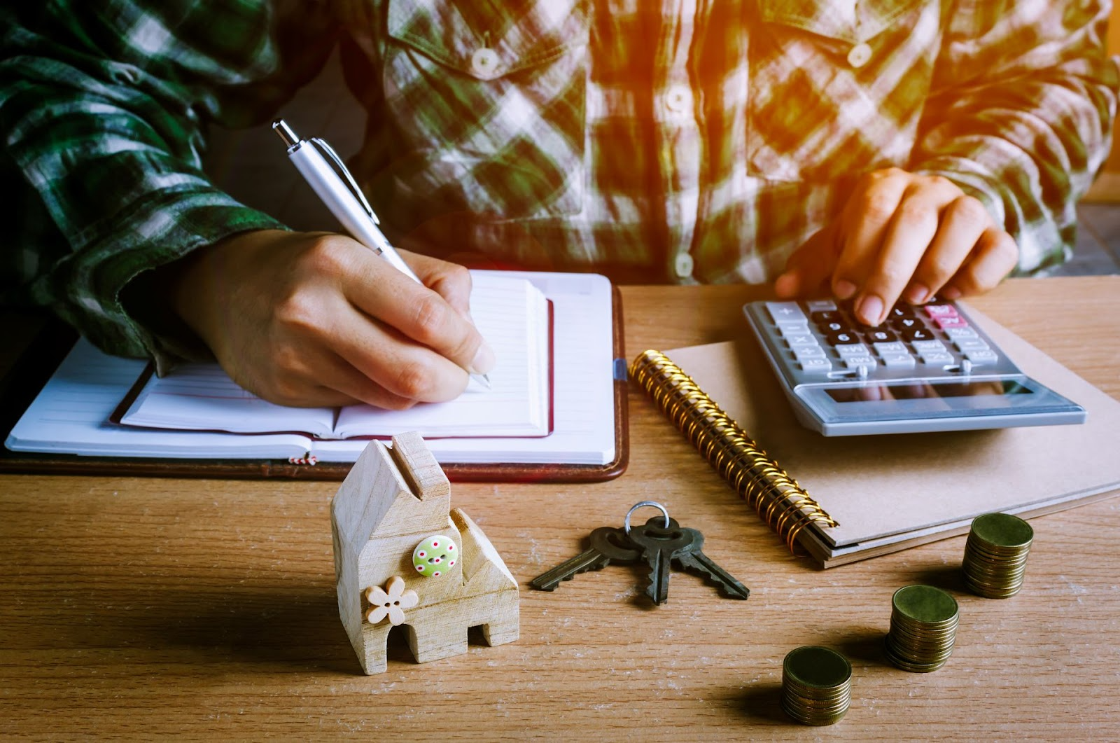 Persona calculando términos de crédito hipotecario con calculadora y modelo casa