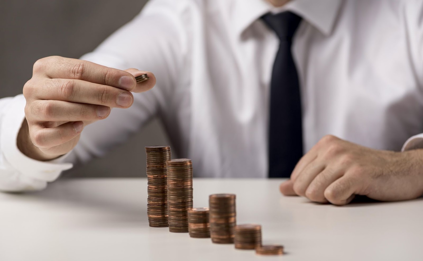 Empresario apilando monedas en orden descendente mostrando gestión de inversiones