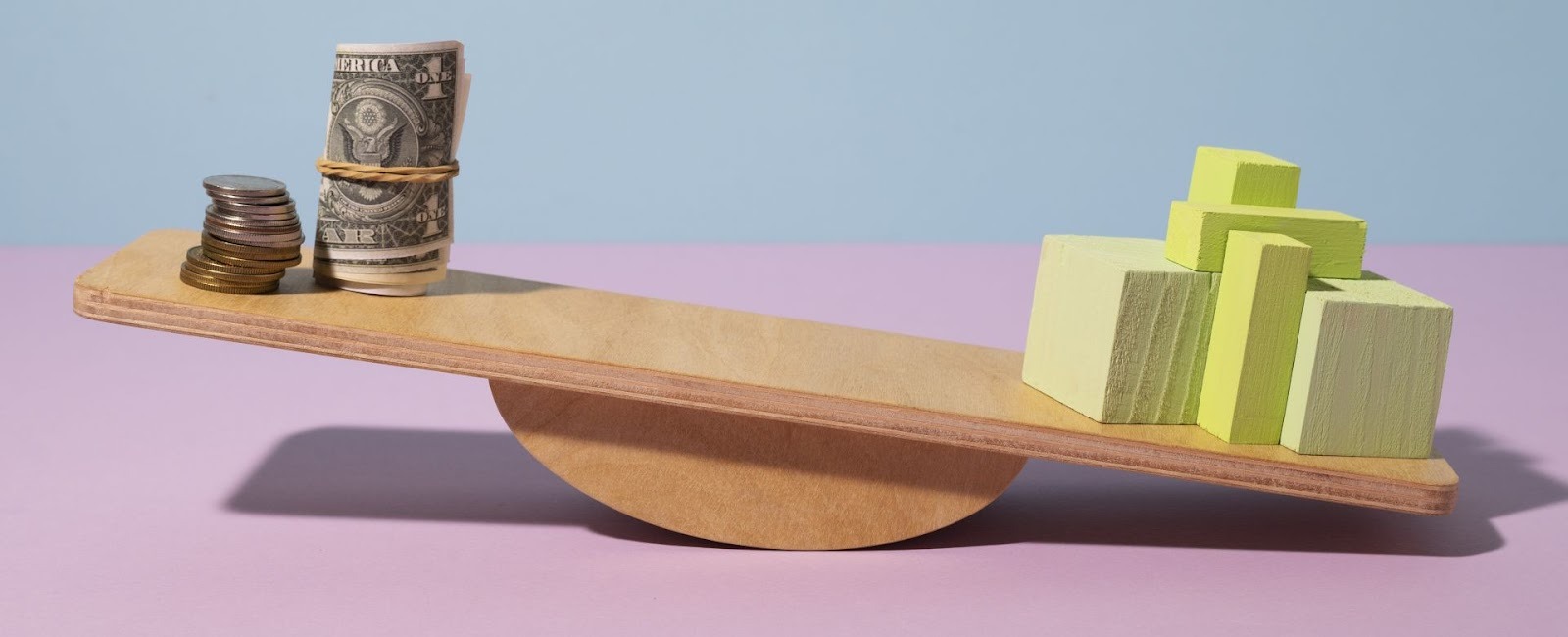 Balanza en equilibrio con monedas y billetes versus bloques verdes representando inversión balanceada