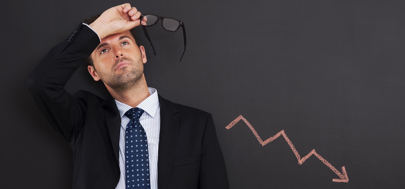 Empresario preocupado mirando hacia arriba con gráfica descendente mostrando pérdidas financieras