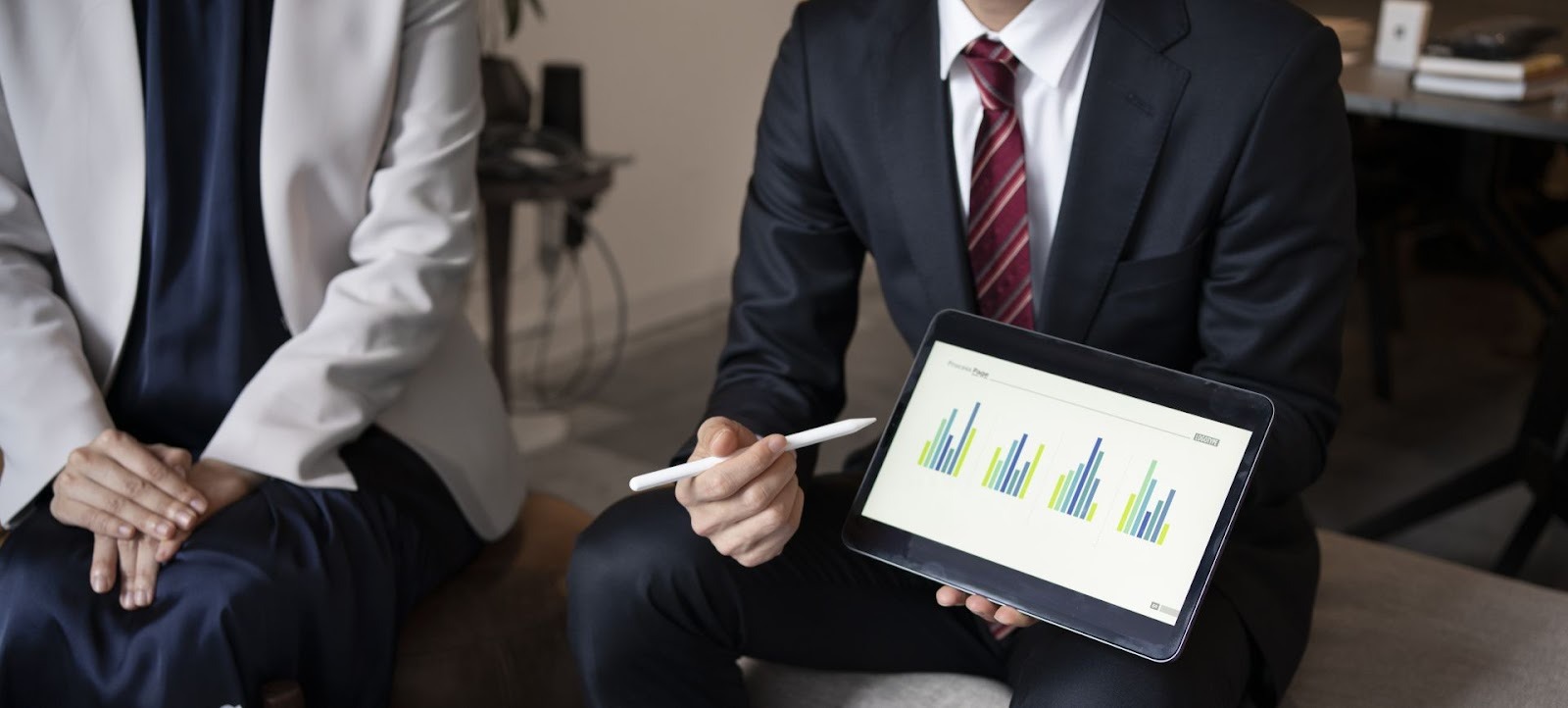 Analista revisando gráficos financieros en laptop mientras toma notas en escritorio con café