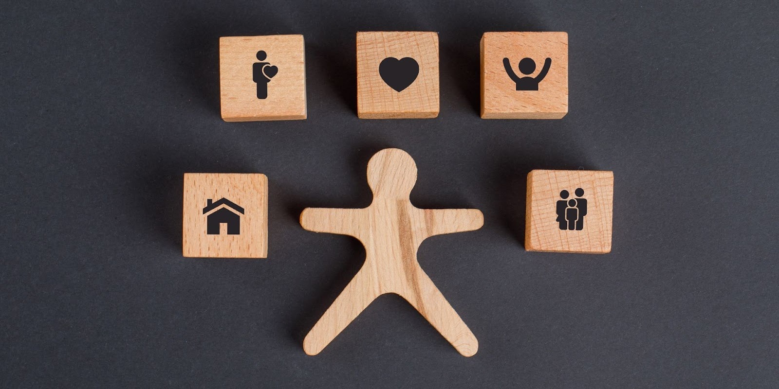 Figura humana de madera rodeada de cubos con íconos de salud, hogar y familia en cada etapa