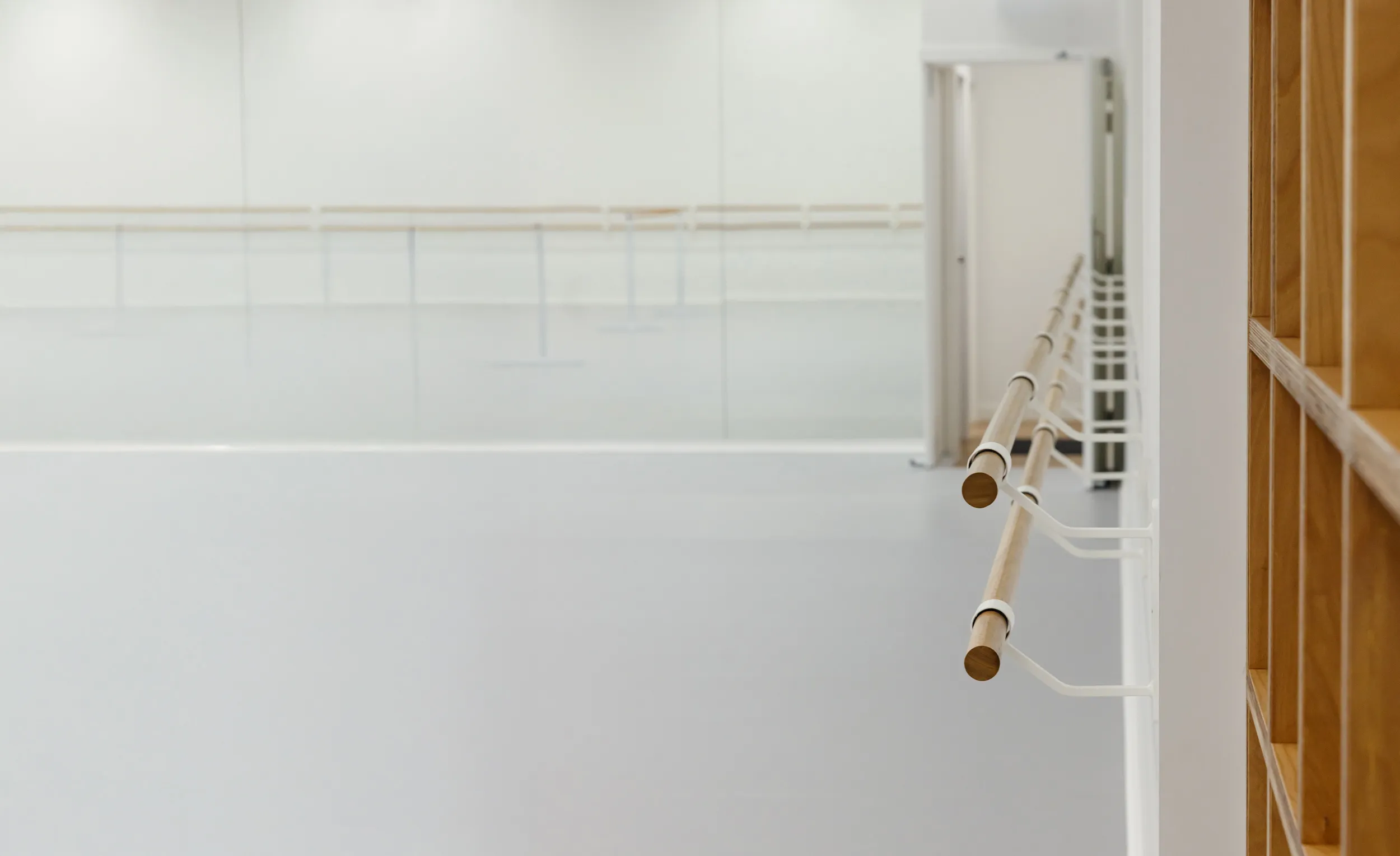 Empty ballet studio with wooden wall bars, ballet barre, and large wall mirror.