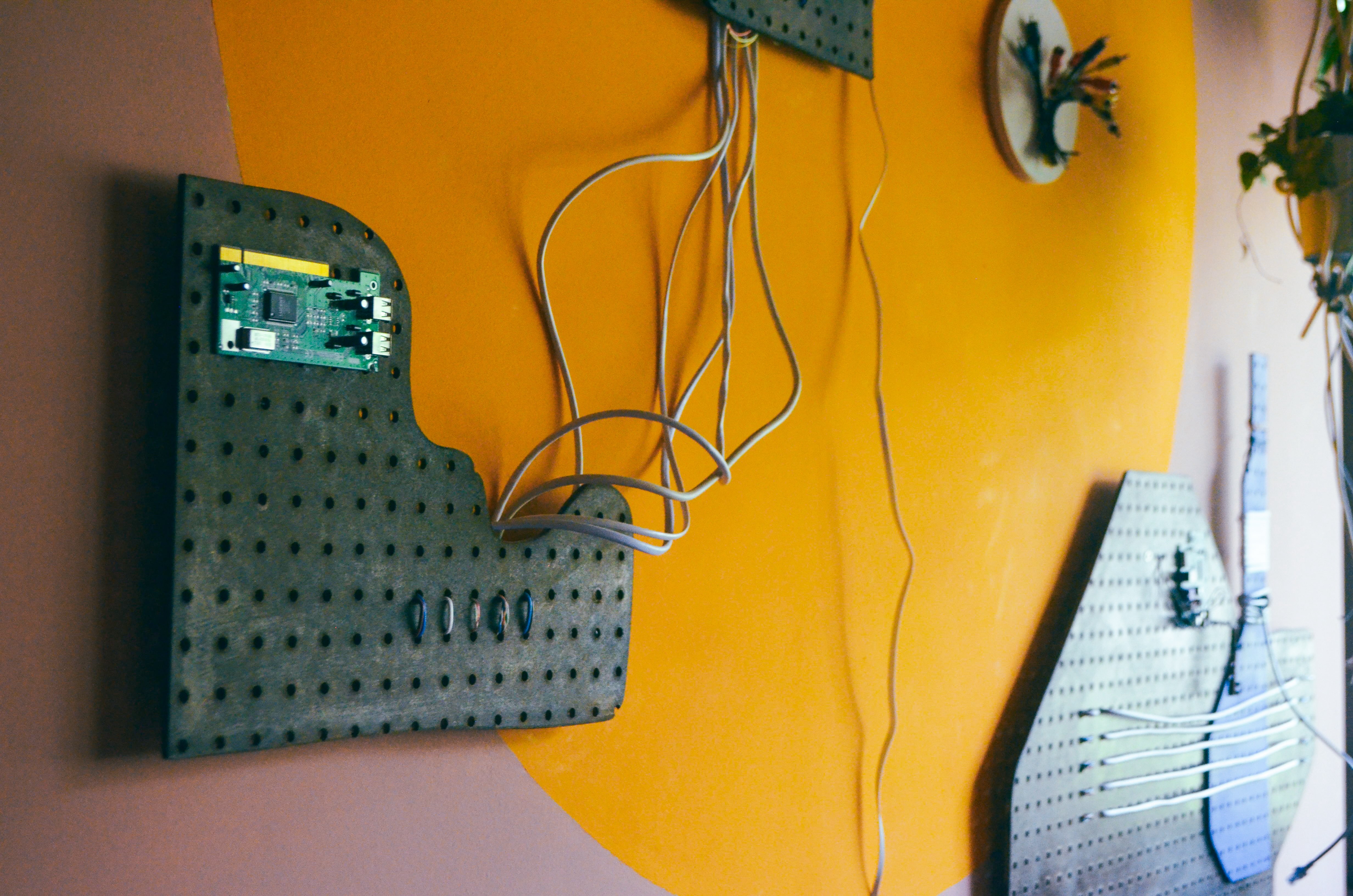 Wanddetail in de nog in aanbouw zijnde hotelkamer “Unplug & Rewire” van hotel De Groene Afslag. Aan de muur een kunstwerk van een stuk moederbord, snoeren en kabels. 