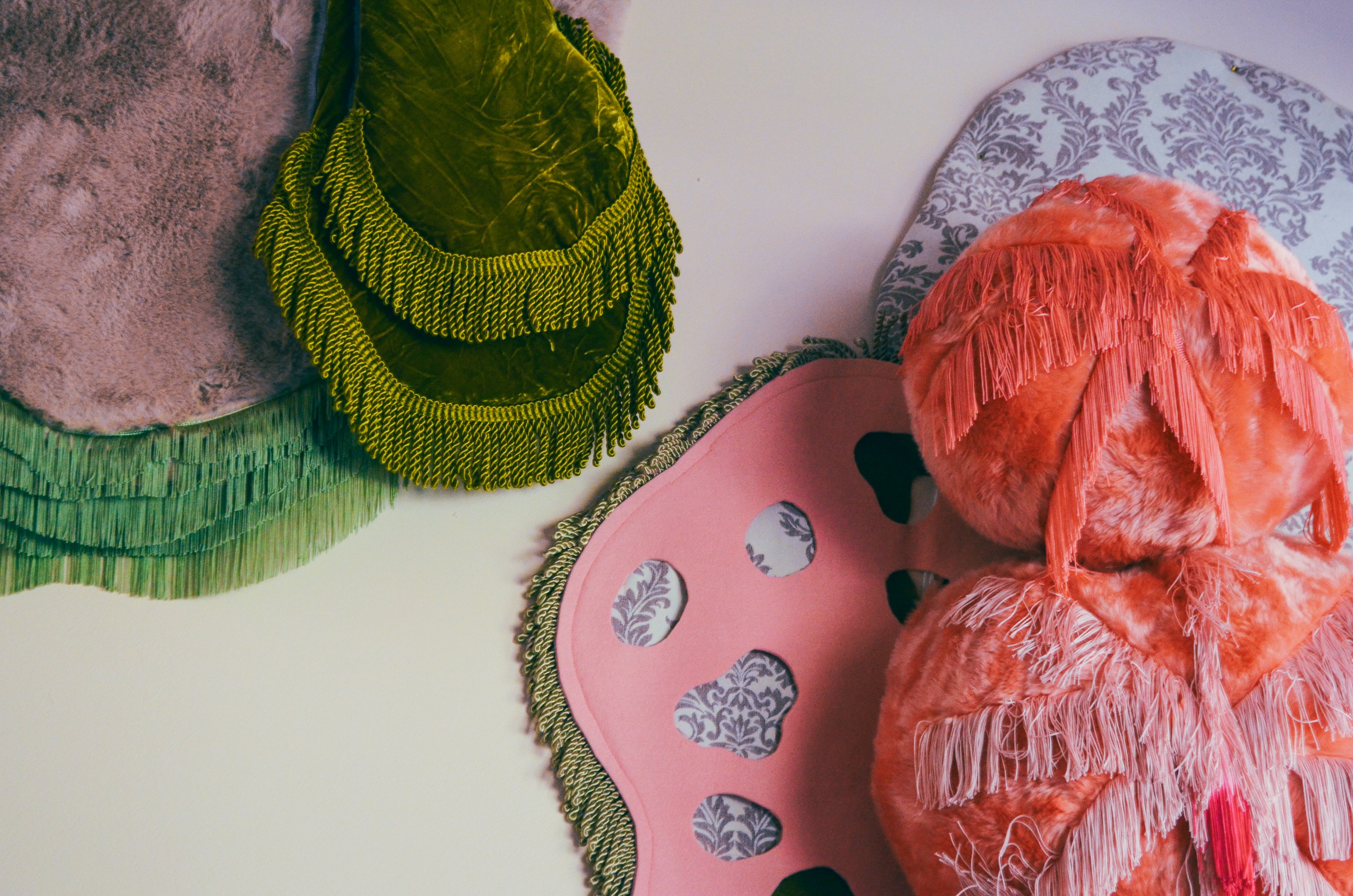 Wanddetail van de nog in aanbouw zijnde “Alice in Fluffyland Kamer” van hotel De Groene Afslag. Op de witte muur een abstract driedimensionaal kunstwerk van zachte textiel met meerdere kleuren, patronen en structuren.