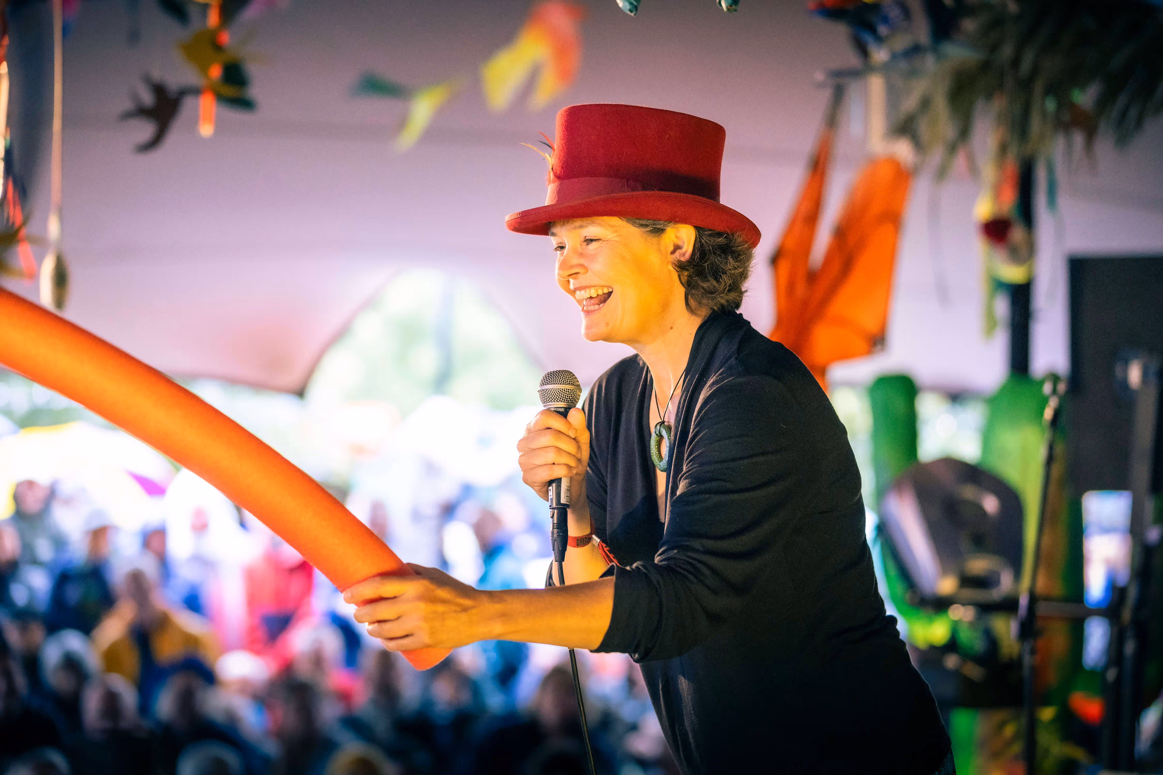 Kate Raworth, bedenker van het economische "donut" model, staat lachend op een podium met microfoon in de hand. Op de achtergrond is een luisterend publiek zichtbaar.