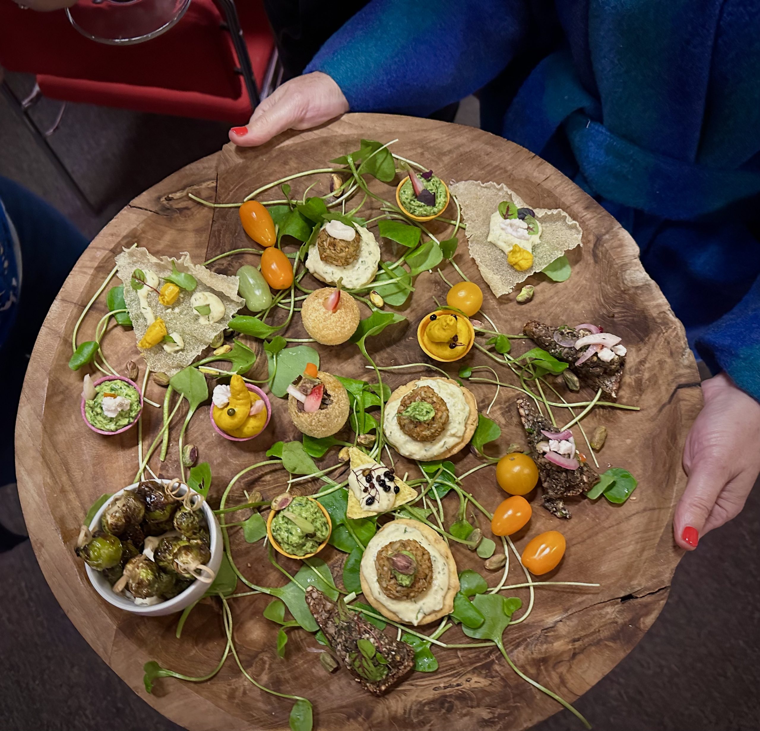 Borrelplank met diverse plantaardige hapjes vastgehouden door een persoon