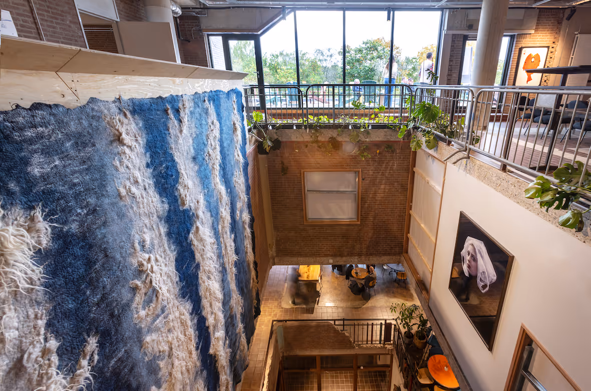 Grote open ruimte in De Groene Afslag met daarin een blauw wandkleed