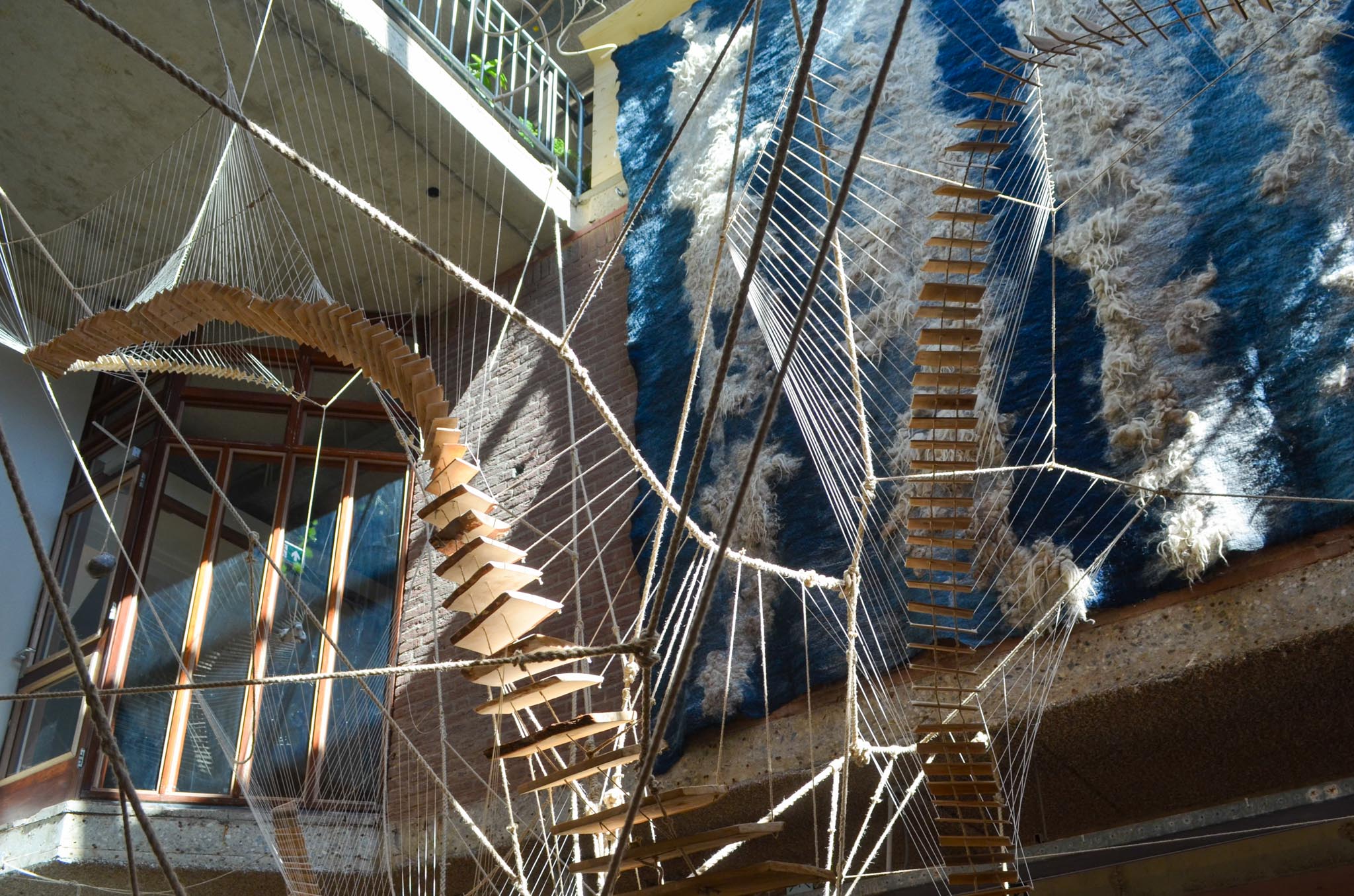 Kunstige trap die tot hoog in een ruimte rijkt met op de achtergrond een blauw wandkleed.