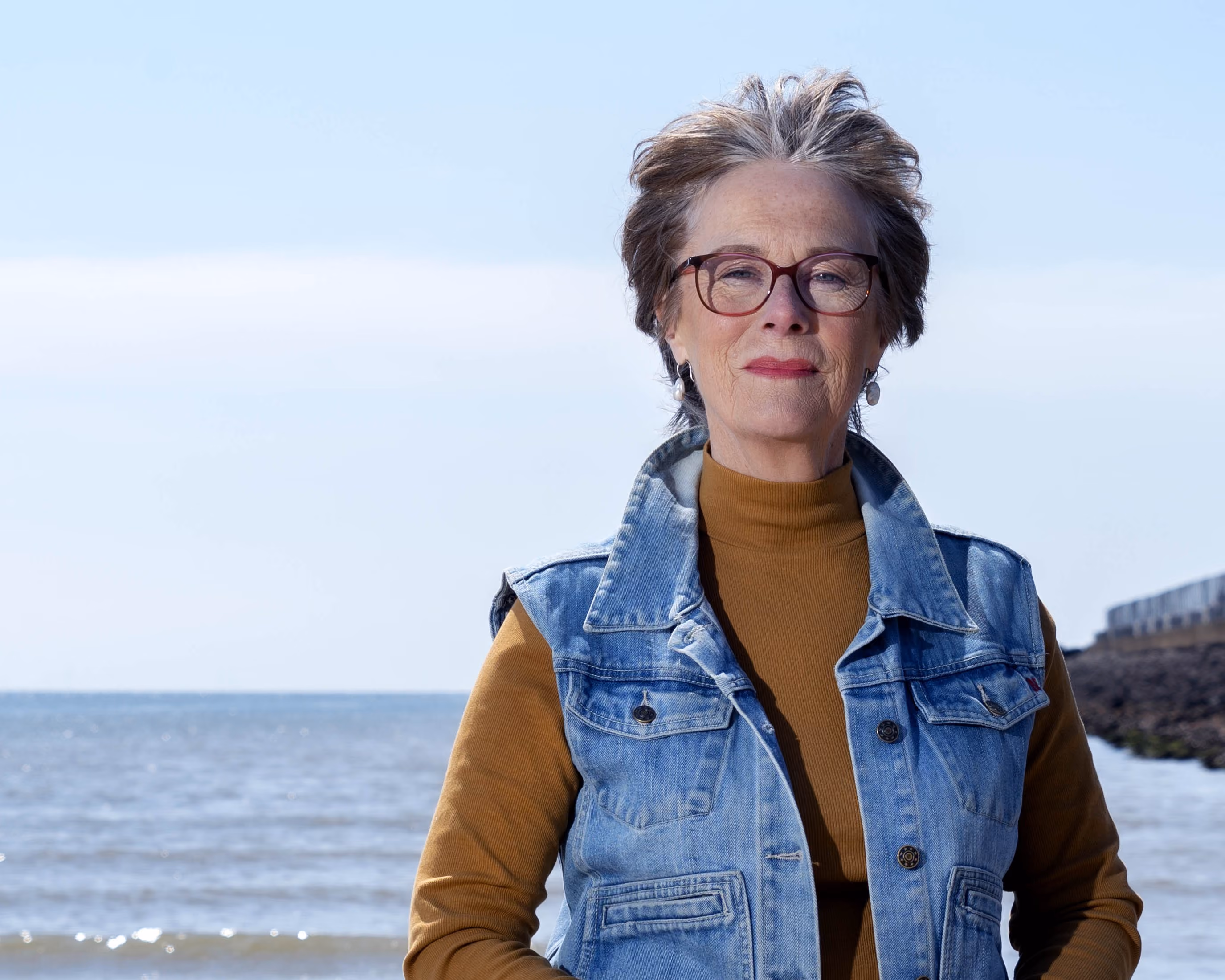 Portret van Arita Baaijens met een strand op de achtergrond