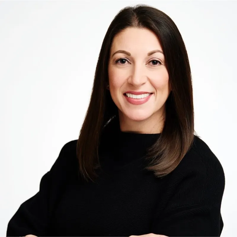 Smiling woman with straight brown hair wearing a black top, standing against a white background — client Lindsey from Colorado Wealth Group.