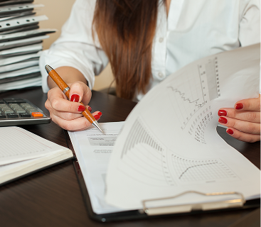 Woman analyzing investment and financial planning reports with a pen and clipboard, representing professional wealth strategy and documentation services at Colorado Wealth Group