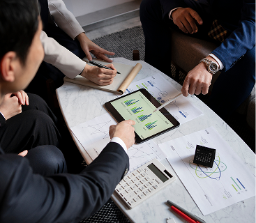 Business professionals collaborating over financial charts and a tablet displaying investment data, representing strategic wealth management planning at Colorado Wealth Group in Denver, CO