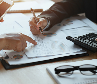Two professionals reviewing financial reports and investment performance charts alongside a calculator and documents, reflecting personalized wealth management and financial planning services by Colorado Wealth Group in Denver, CO