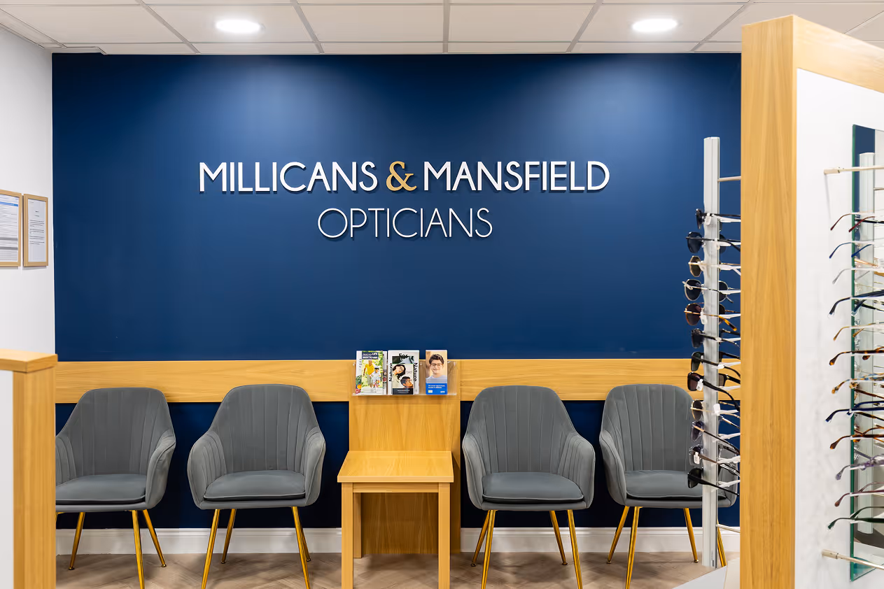 Millicans & Mansfield Opticians waiting area with gray chairs and eyeglass display