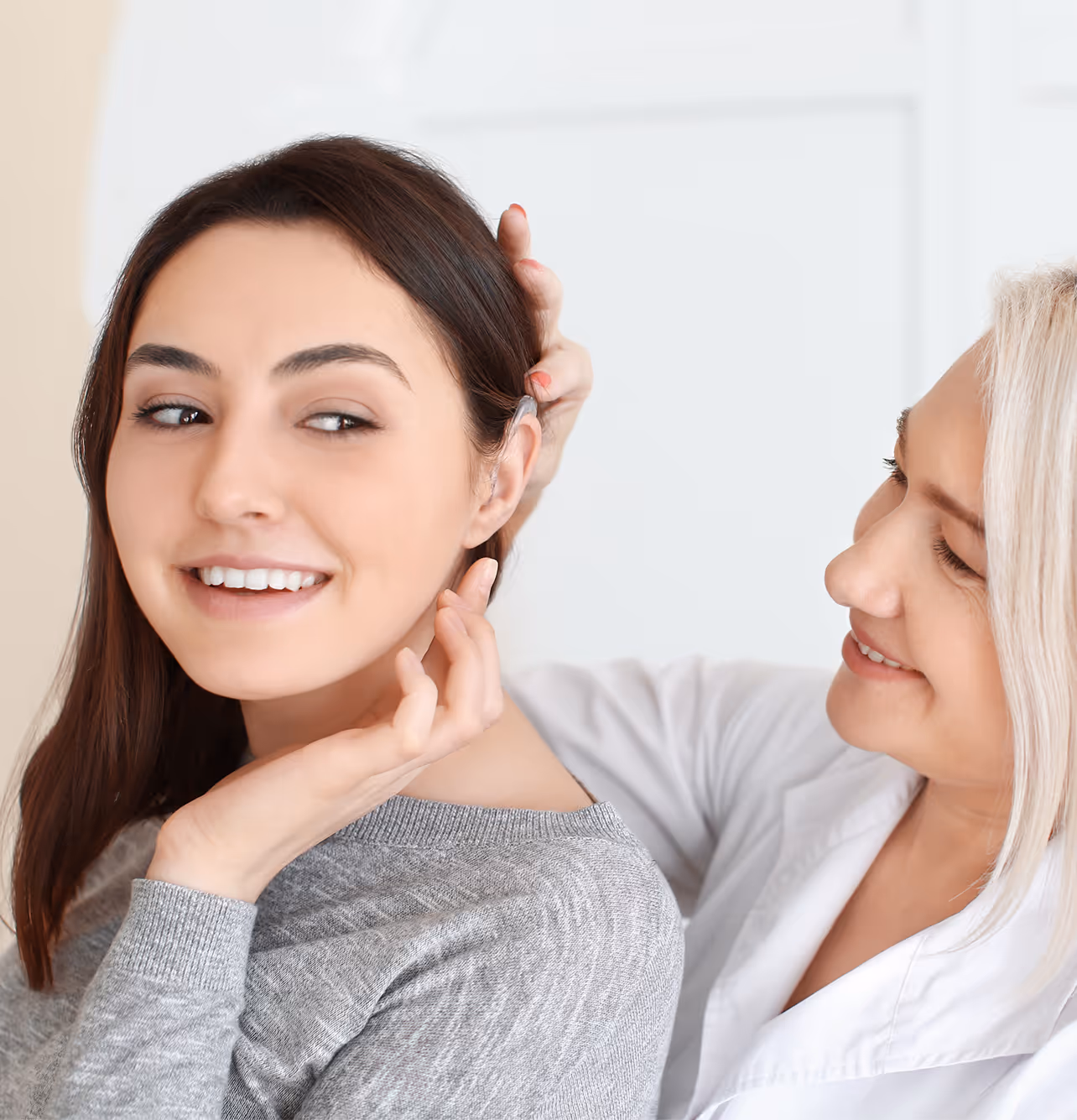 Two women smiling and touching hair in a friendly interaction