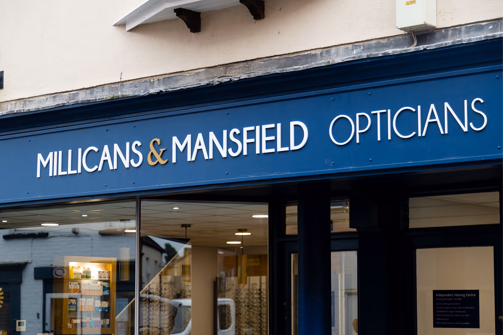 Blue storefront of Millicans & Mansfield Opticians with glasses display