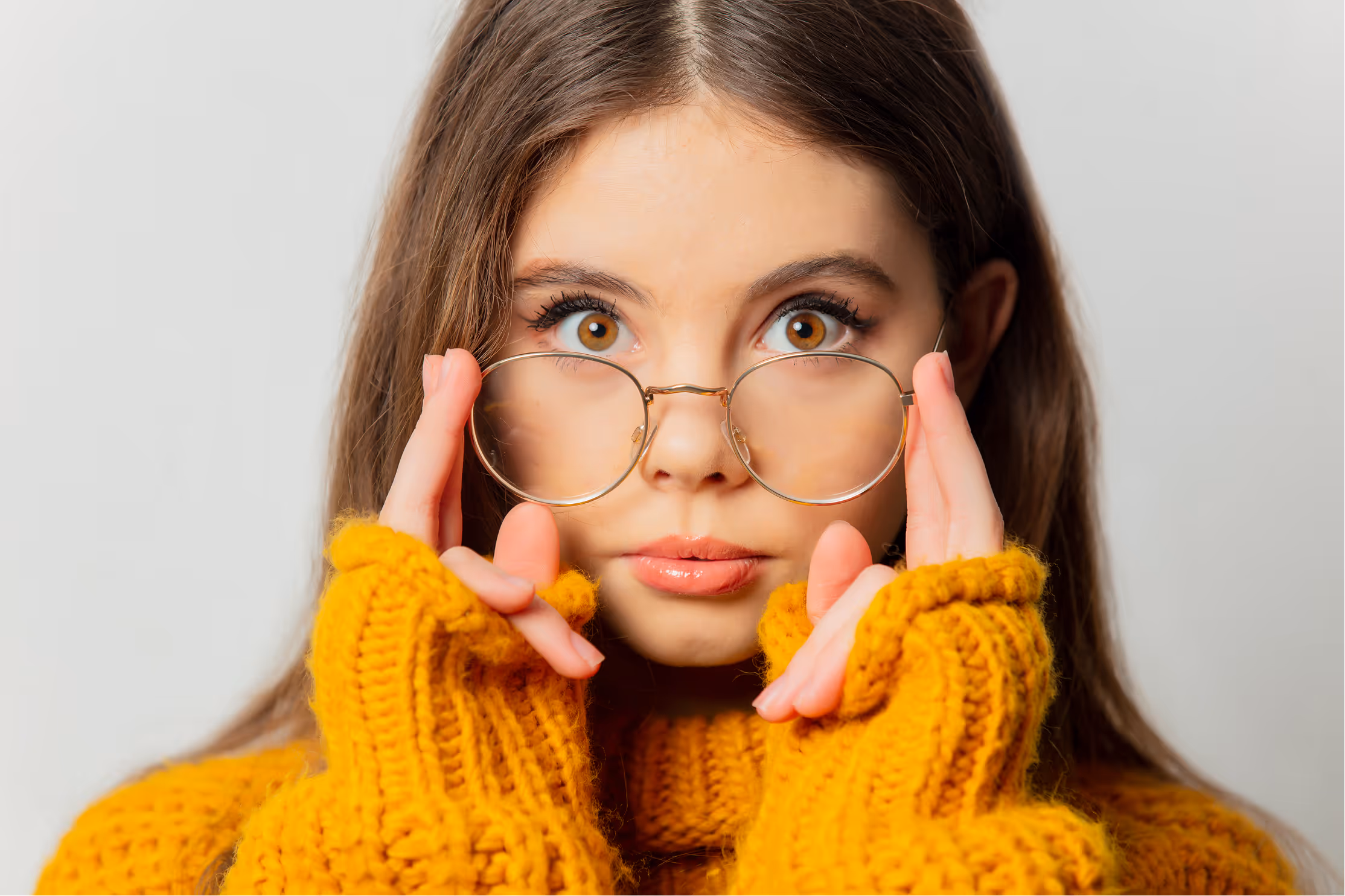Woman in yellow sweater adjusting round glasses with playful expression