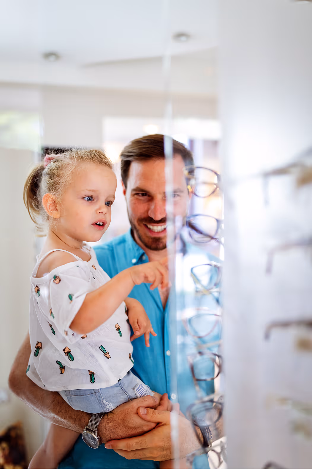 Young child with parent looking at glasses in optometry office