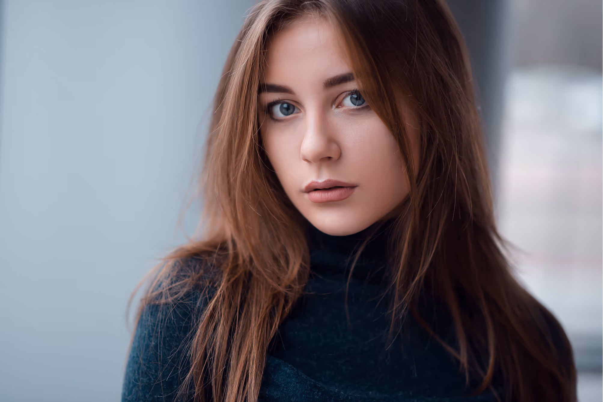 Young woman with long brown hair in black turtleneck looking sideways