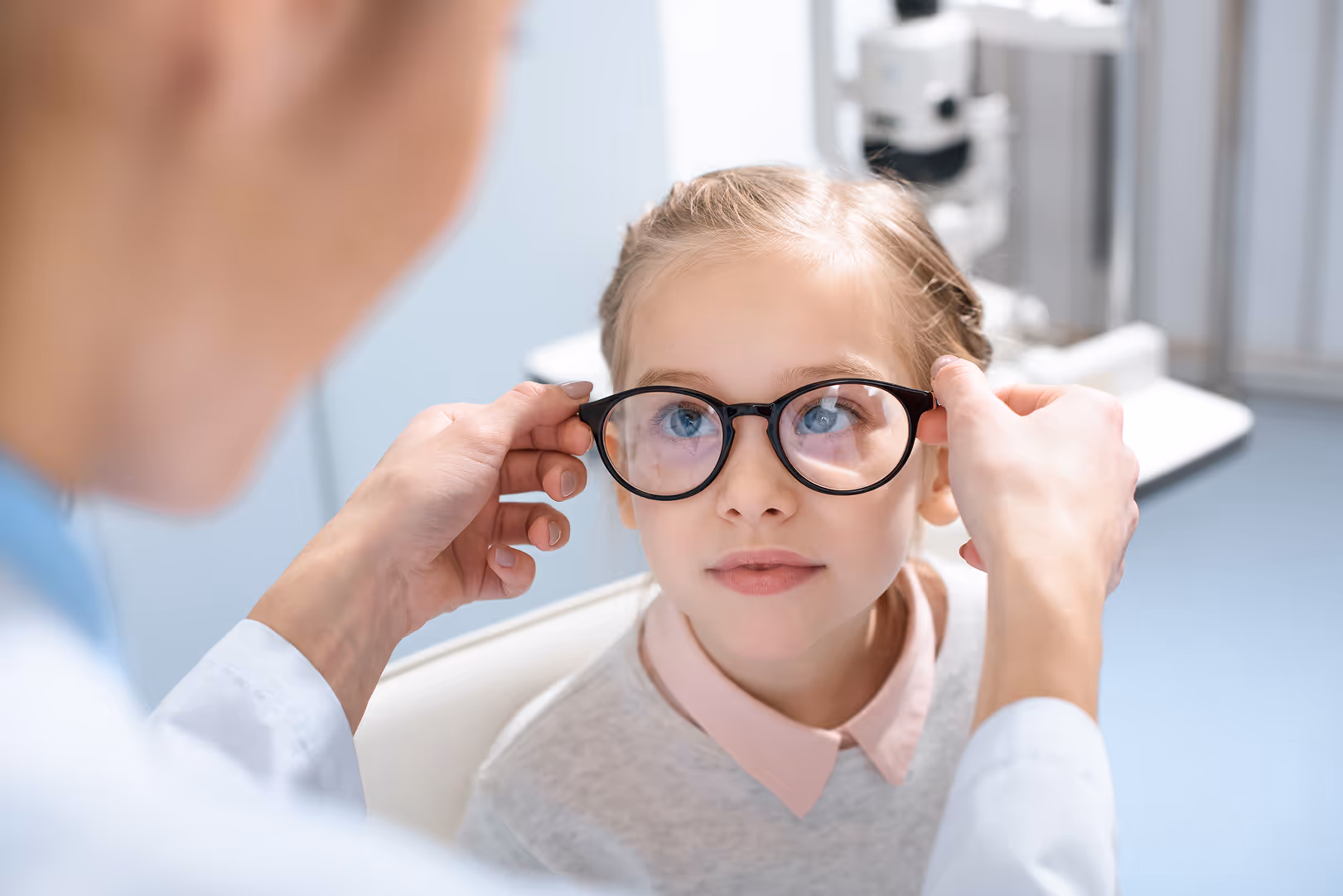 Eye doctor fitting glasses on child during vision exam
