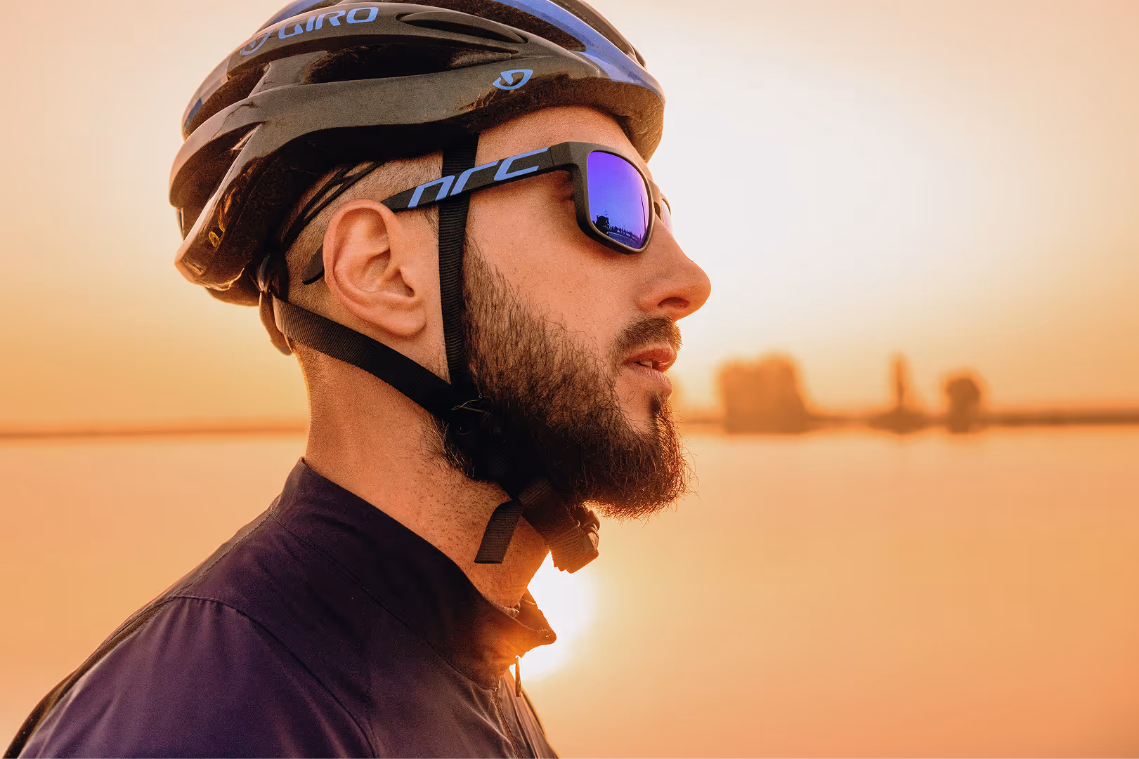 Cyclist in Giro helmet and sunglasses at sunset, side profile view