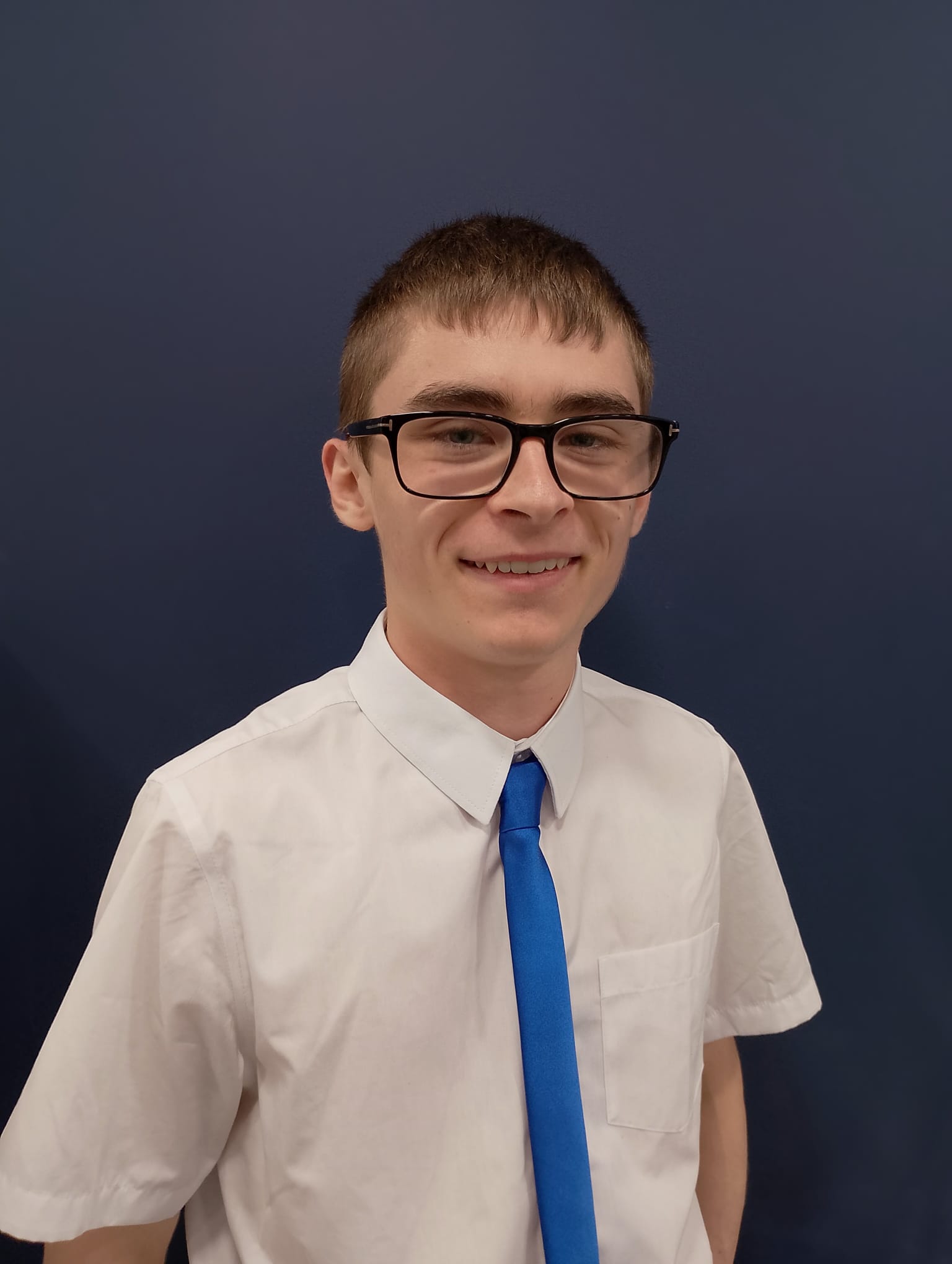 Young person in white shirt and blue tie smiling with glasses