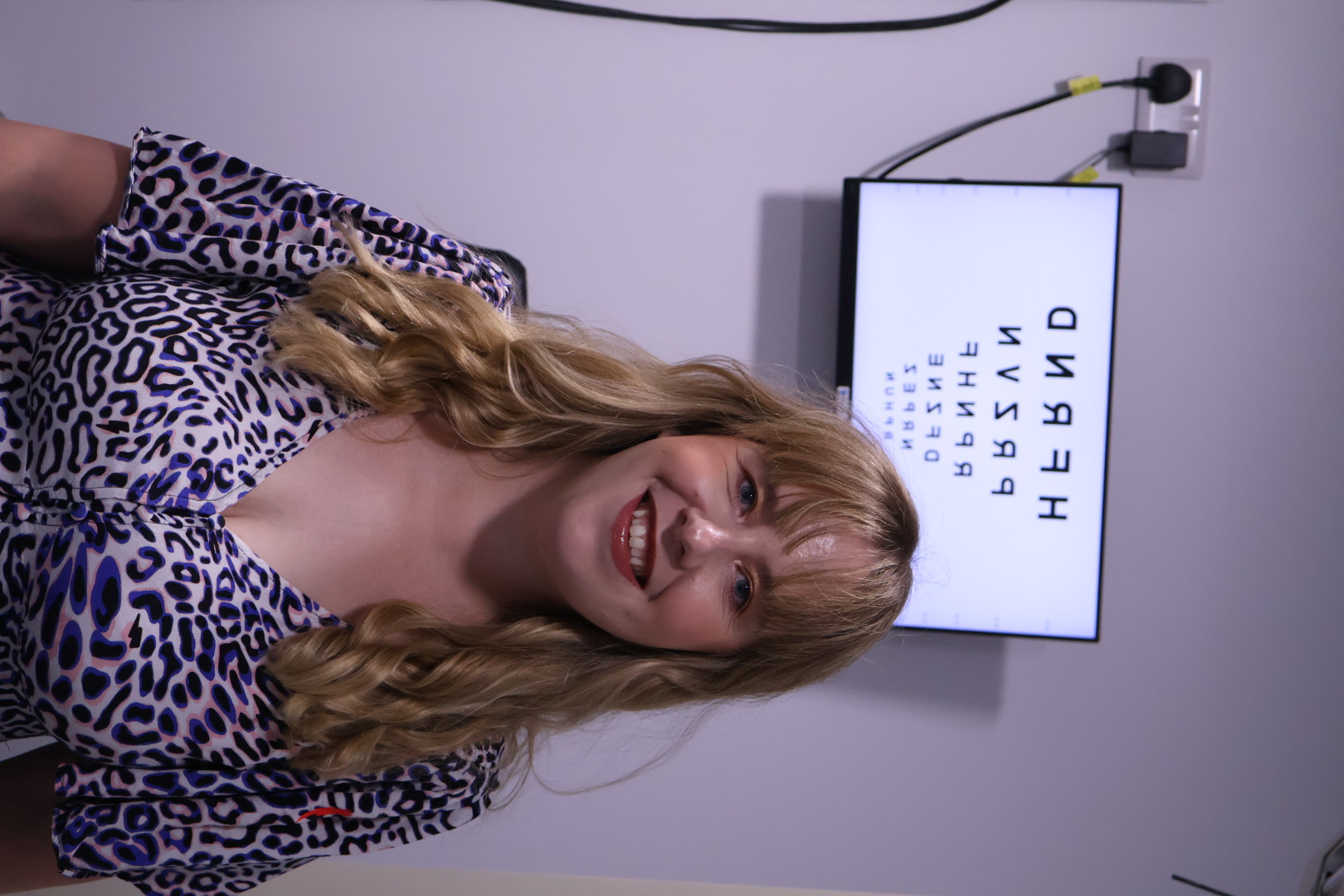Smiling person in leopard print top in front of eye chart