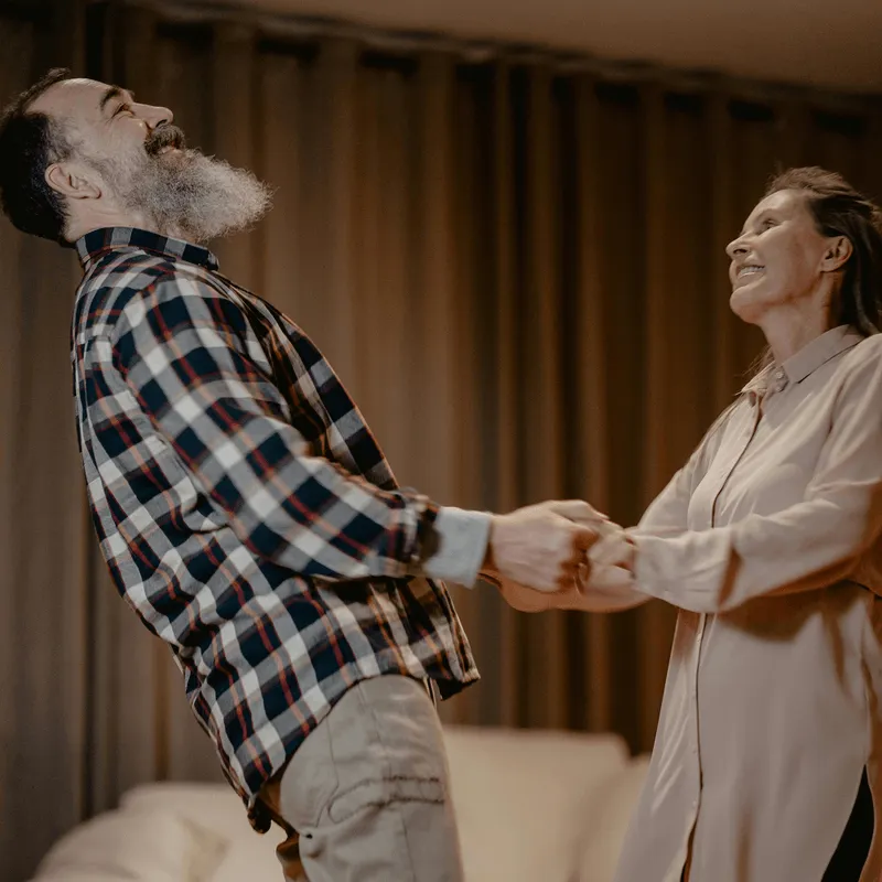 Middled aged couple dressed stylishly holding hands and enjoying time together dancing