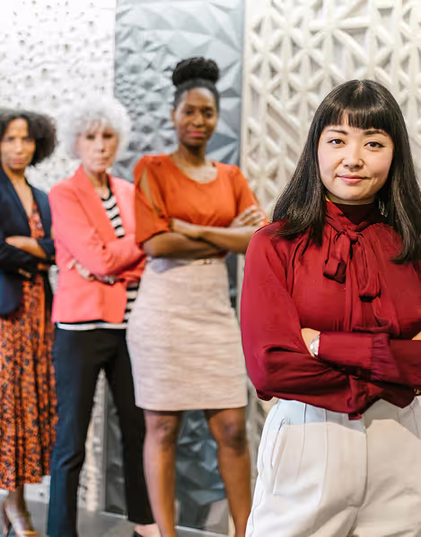 Group of women standing with arms crossed but appear welcoming in an office enviroment