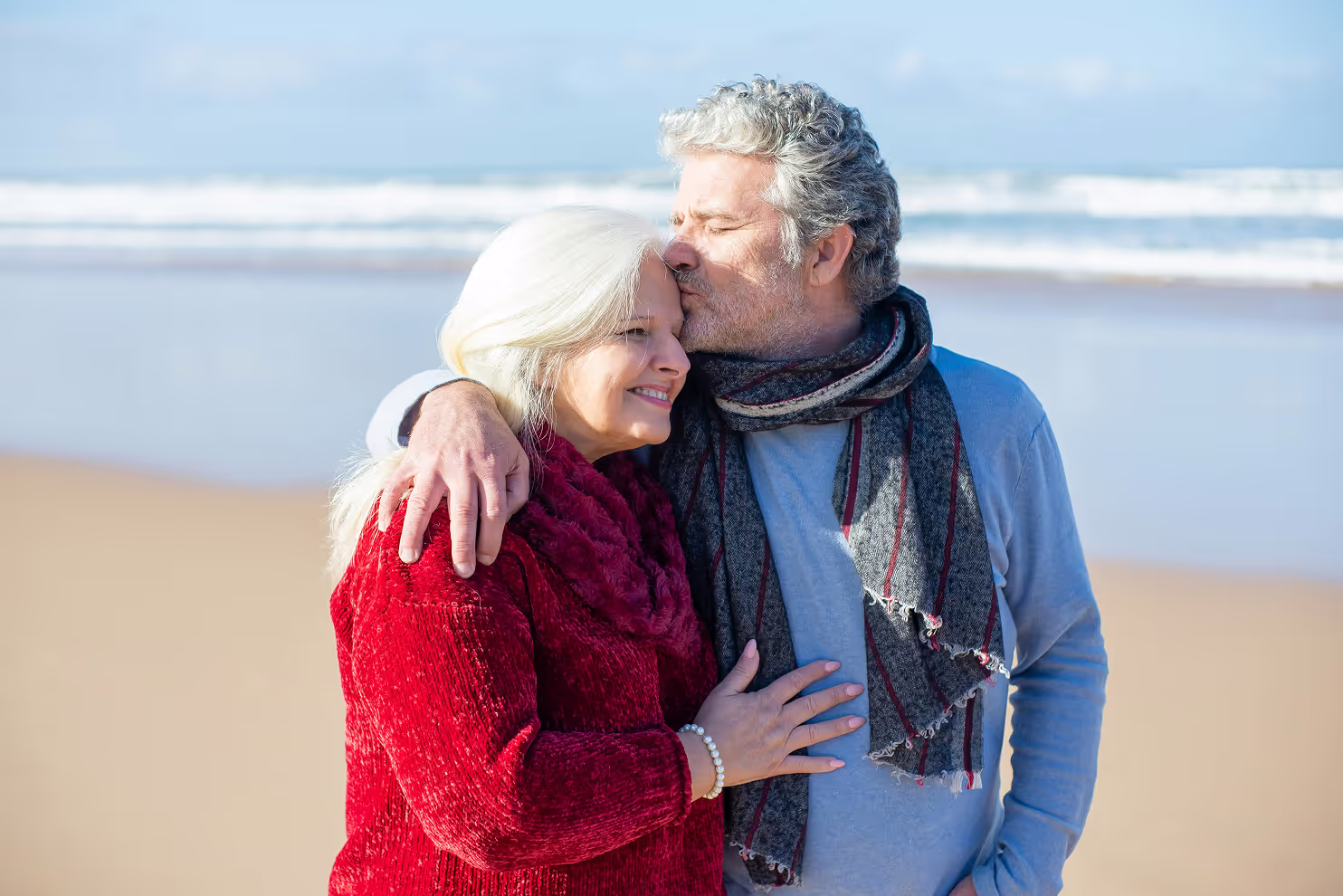 Middle aged couple walking on the beach being loving