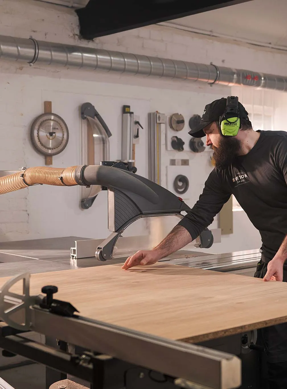 A skilled craftsman working meticulously on raw timber inside the traditional Burton Bespoke woodworking workshop.