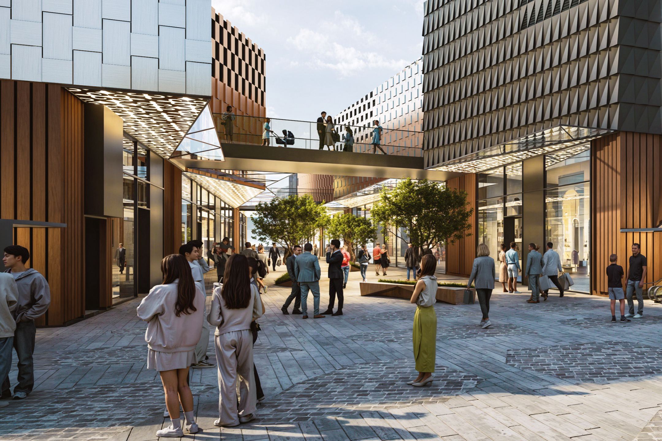 People  in a modern outdoor plaza at Almaty Hillside Outlet, walking on stone paving between wood-clad and metal-panel storefronts under a glass pedestrian bridge.