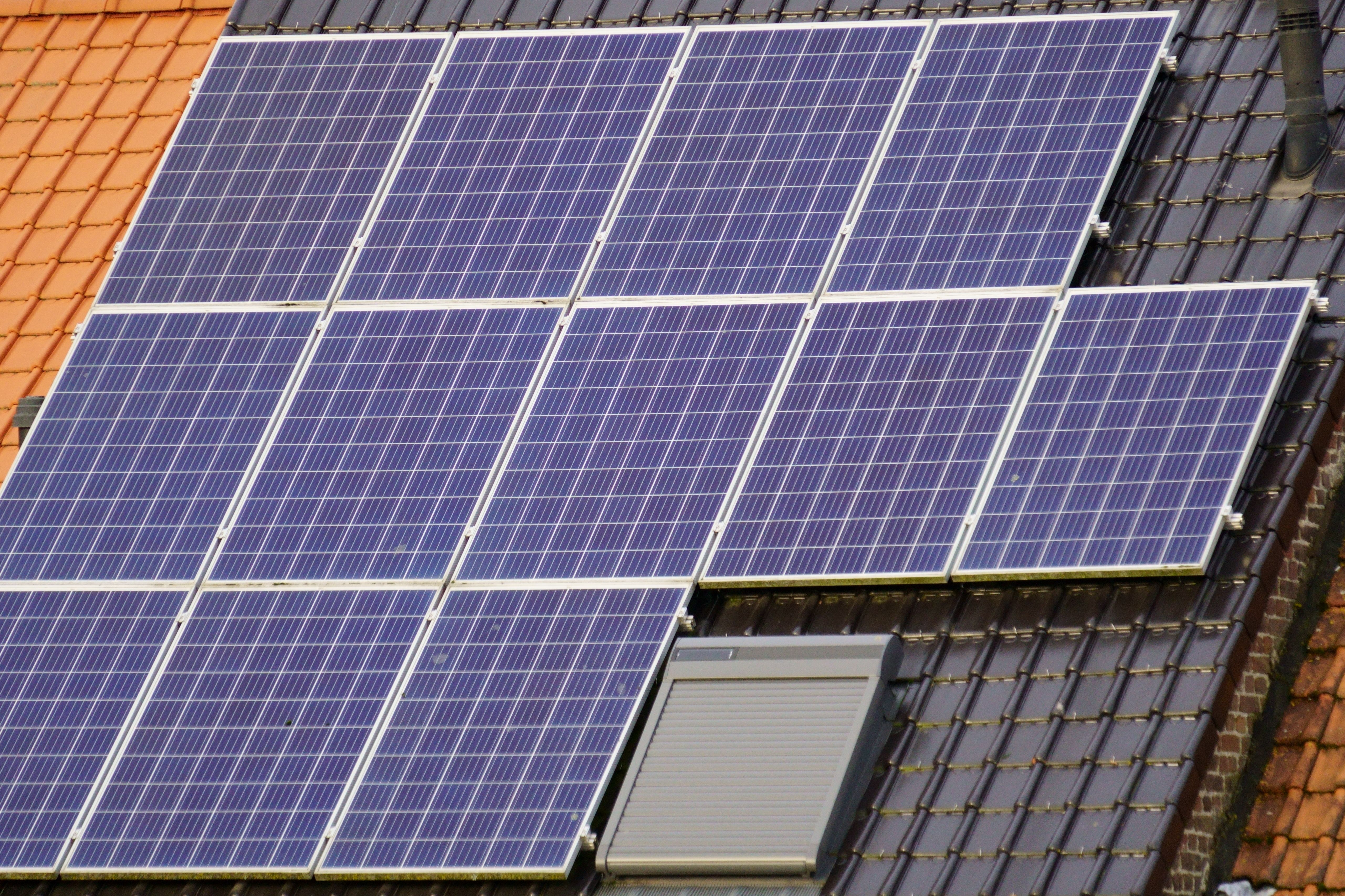 Close-up of solar panels on a tiled residential rooftop under clear sky, illustrating how household self-consumption captures solar generation on site.