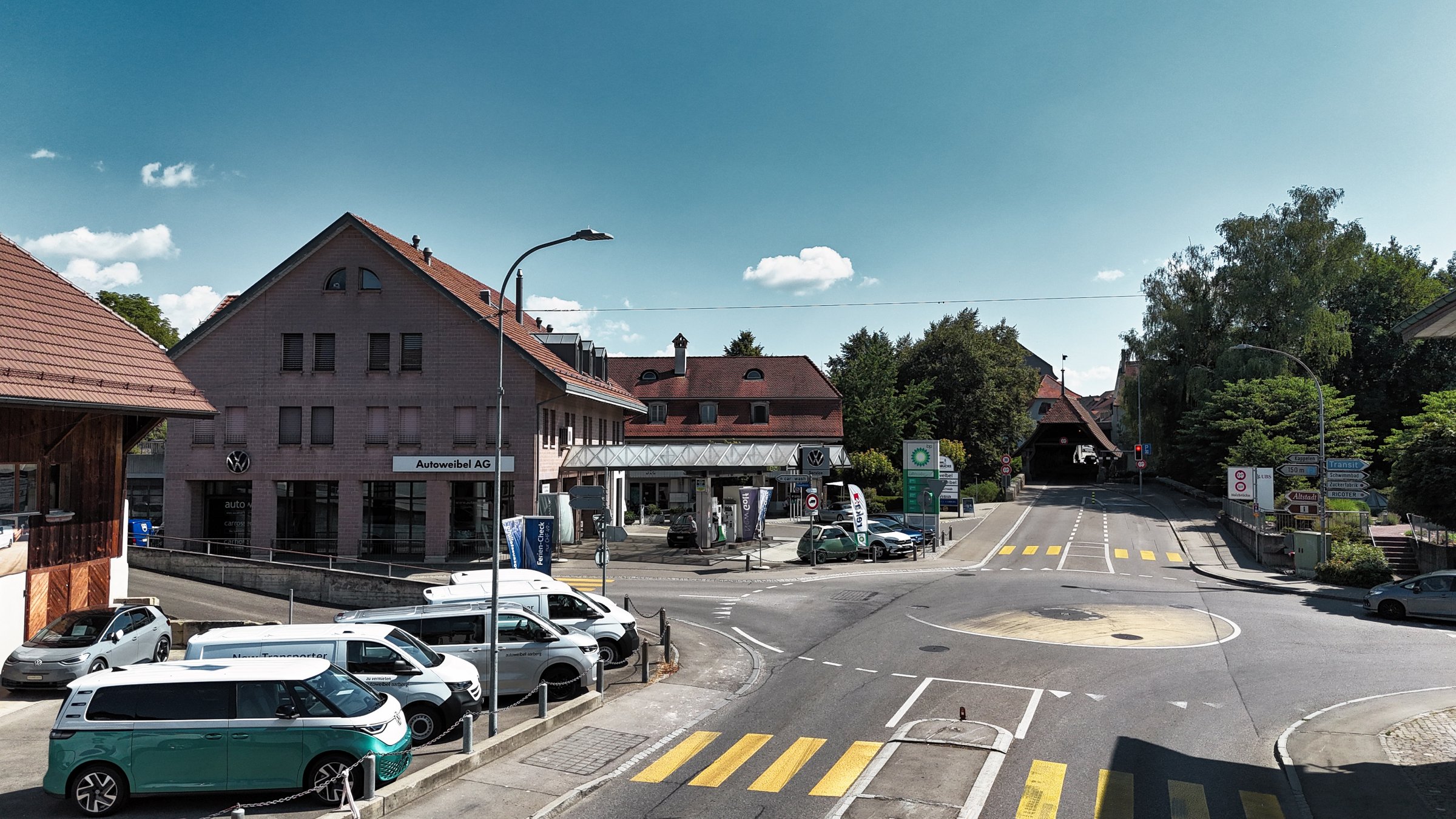 Autoweibel von aussen, in Vordergrund Volkswagen Nutzfahrzeuge im Bestand und rechts neben dem Betrieb die Holzbrücke in die Altstadt von Aarberg