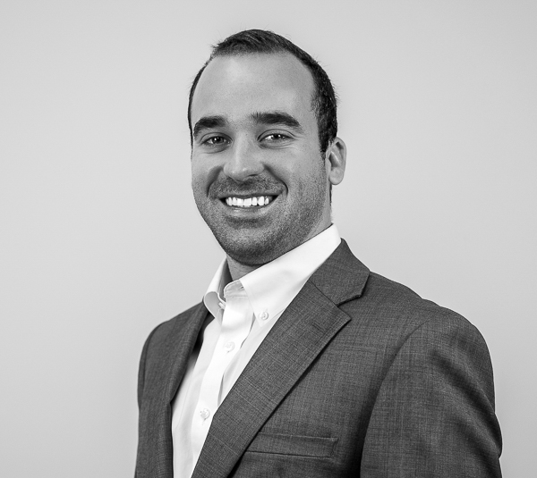 Matthew Conley, Operations Coordinator at Colorado Wealth Group, smiling confidently in a suit jacket and white shirt, photographed against a plain background.
