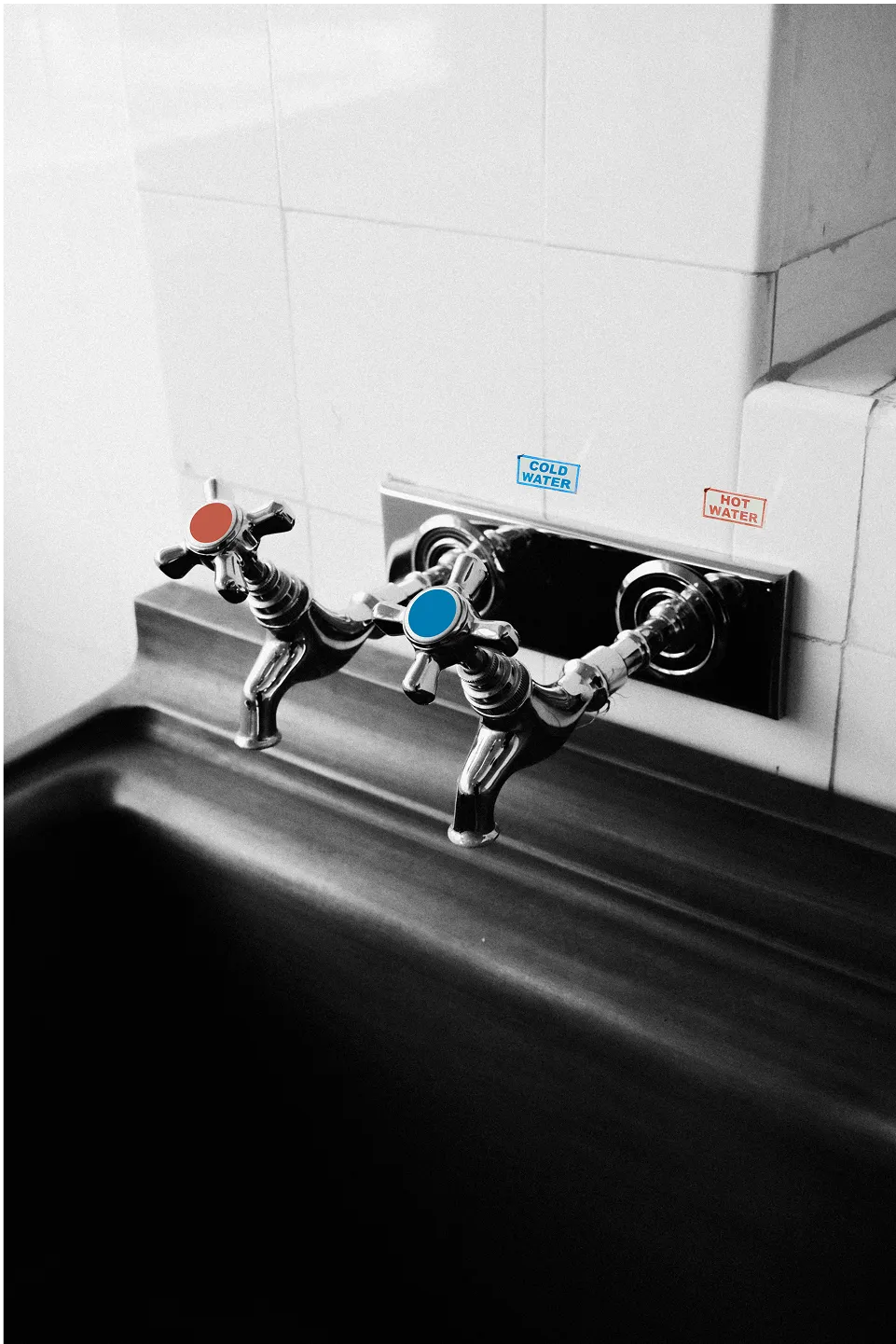 A pair of water taps labeled hot and cold, but the handles are swapped - hot dispenses cold water and cold dispenses hot.