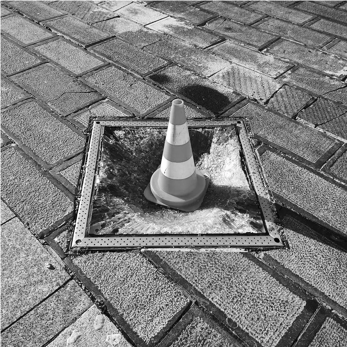 A traffic cone placed on top of shattered perspex glass.