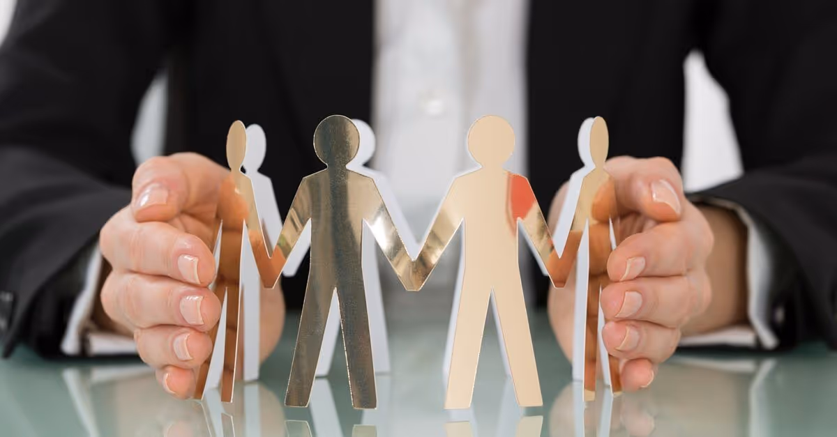 Man supporting a group of paper human figures holding hands