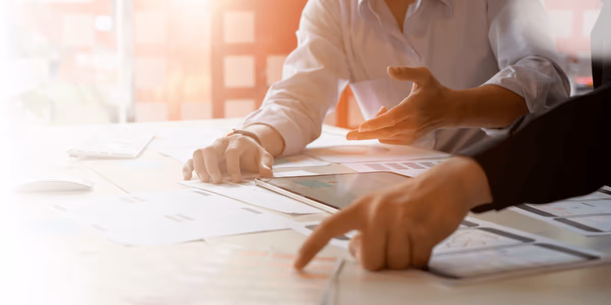 Managers sat at on office desk pointing at a plan
