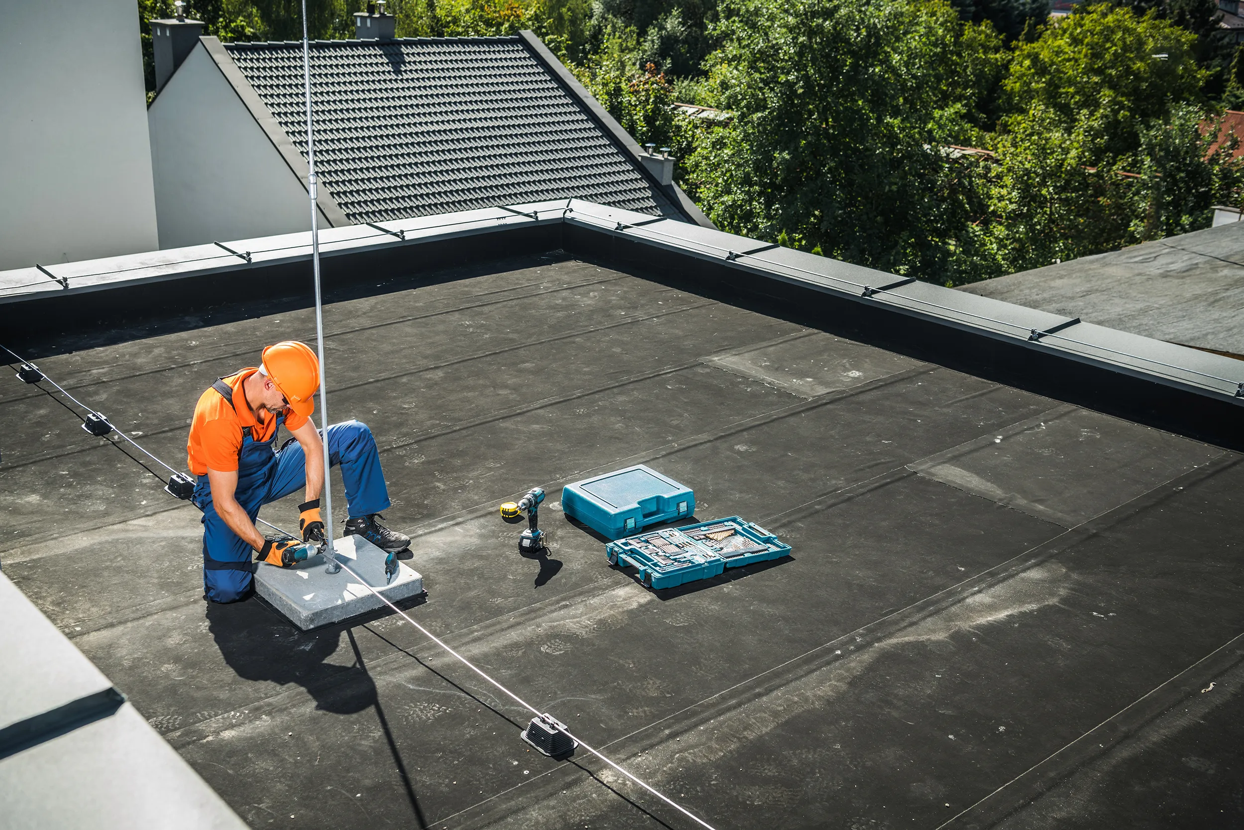 Technieker monteert een opwaartse vangleider op een plat dak als onderdeel van een bliksembeveiligingssysteem