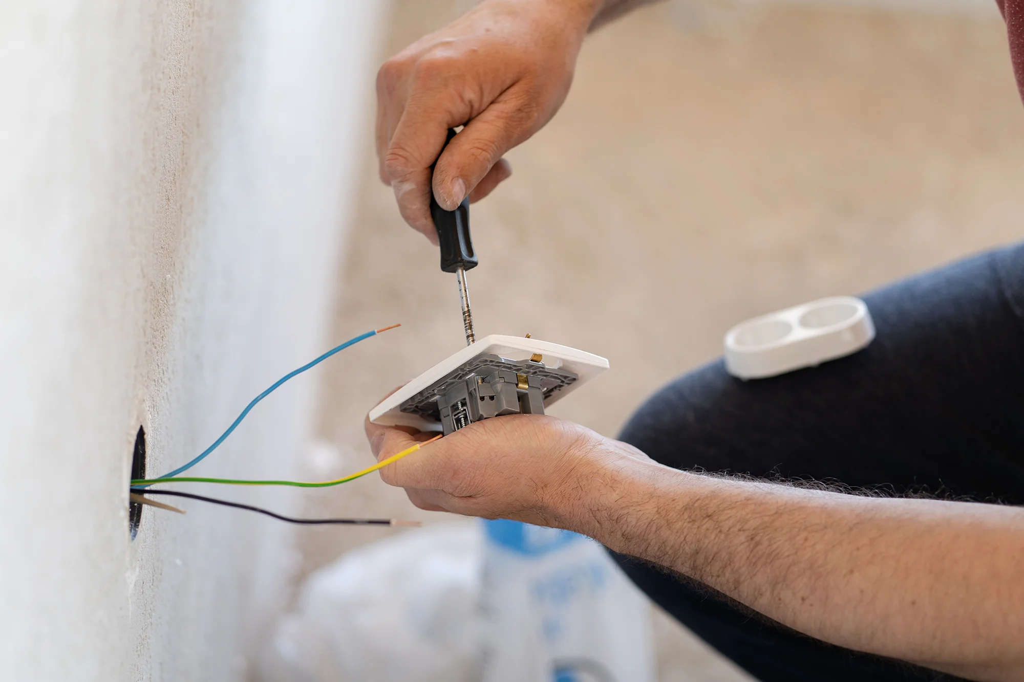 Electrician’s hand wiring a wall socket during residential installation